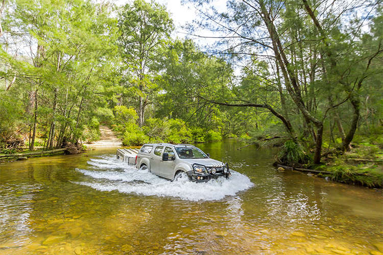 4WD towing a camper trailer through a river