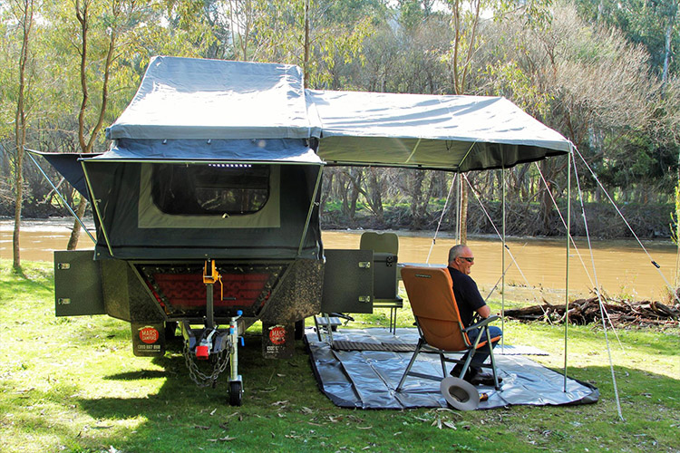 Open camper trailer with a man sitting