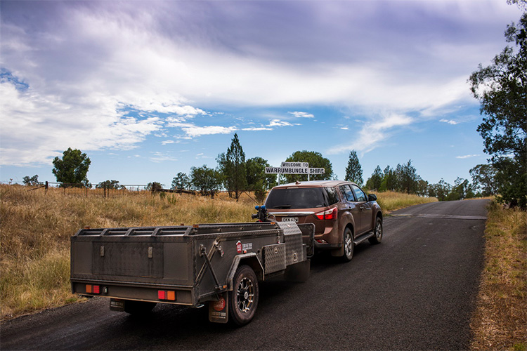A 4WD towing a camper trailer through the country
