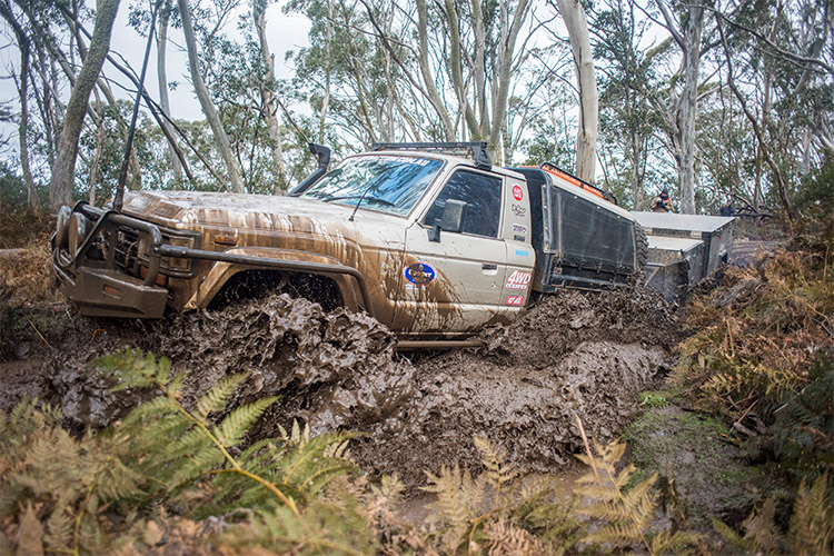 A muddy 4WD driving with a camper trailer