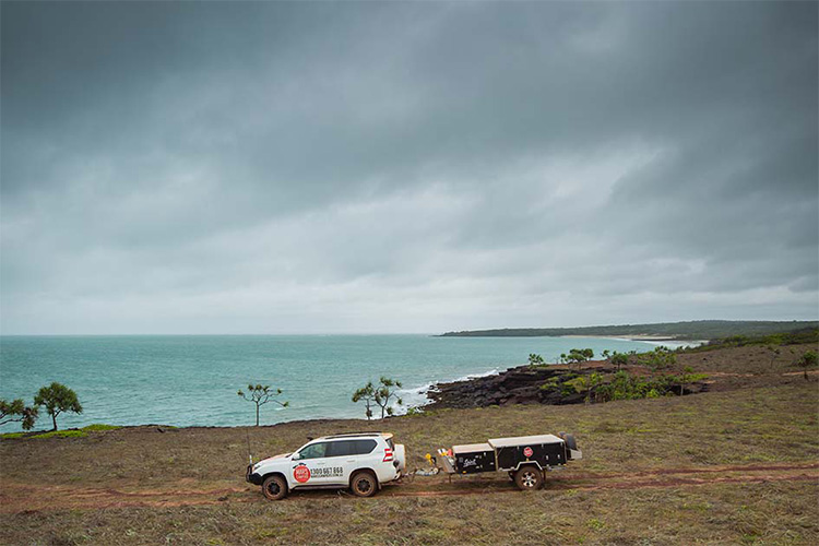 4WD towing a camper trailer along a coastline