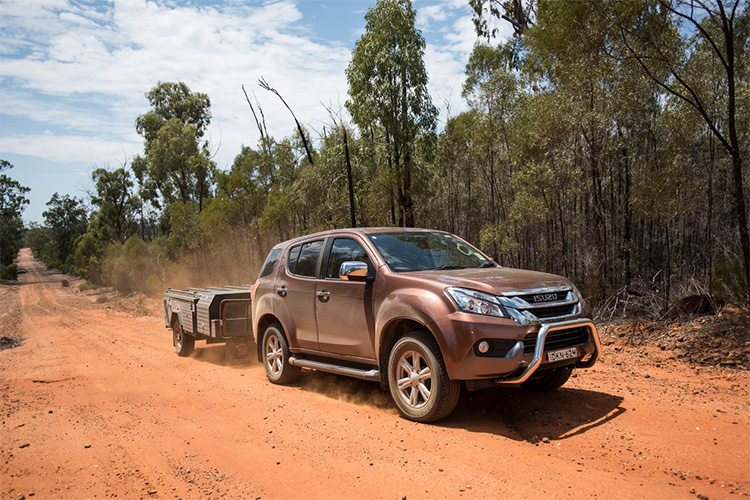 4WD towing a camper trailer through dusty red sand