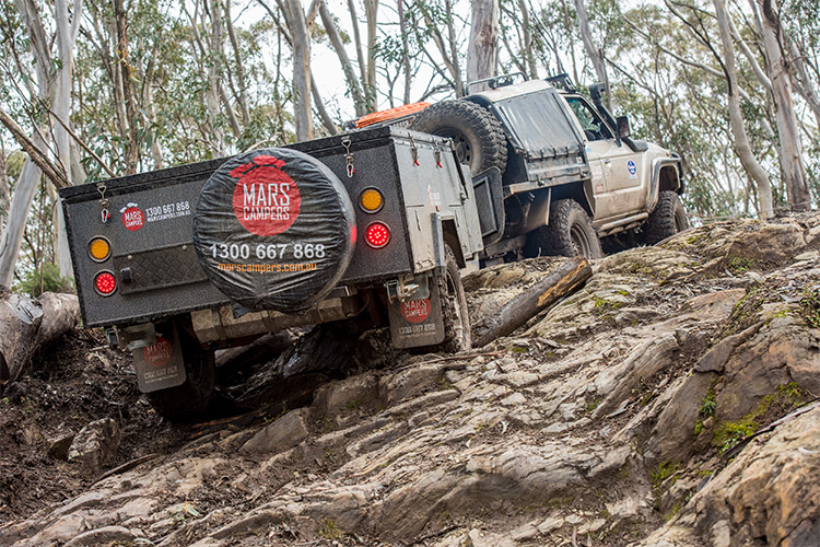 4WD and camper trailer driving up a muddy hill
