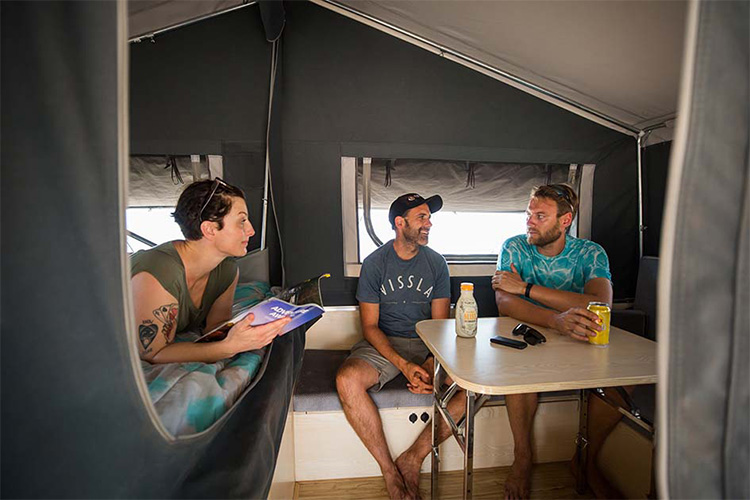 Two guys and a girl talking in a camper trailer