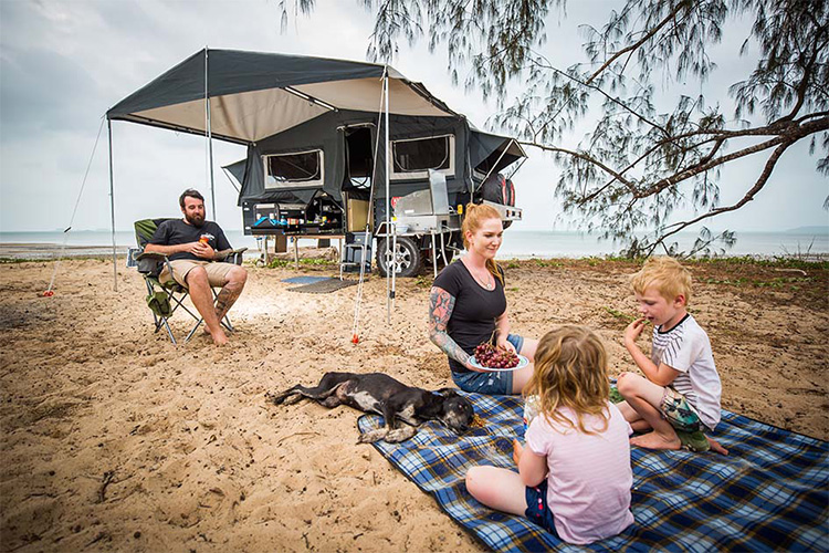 Family having a beach picnic with their camper trailer