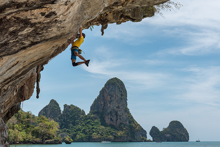 Guy with yellow shirt climbing a rock