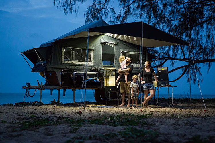 Family enjoying by the beach in the night with a camper