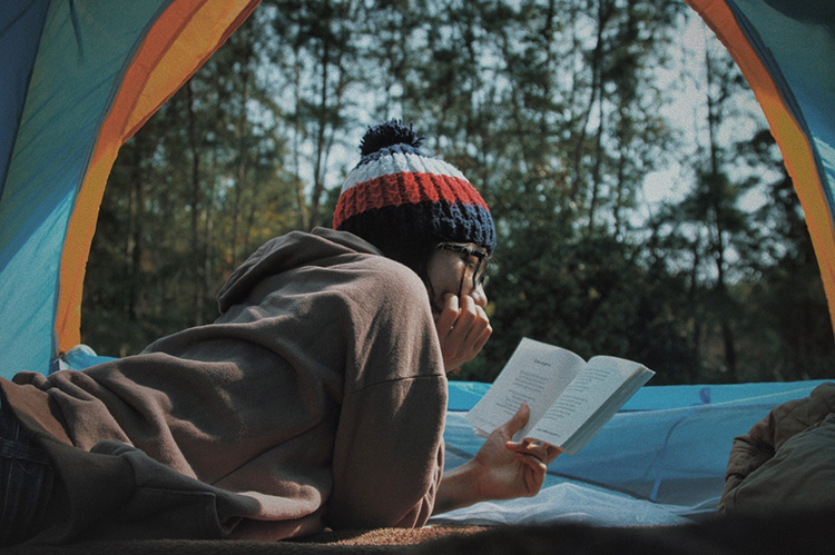 Girl reading a book in camp