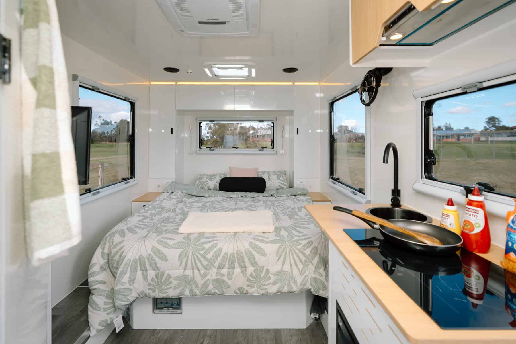 Mars 17HR lightweight on road couples caravan interior alternate view of living space with induction cooktop sink and queen sized island bed